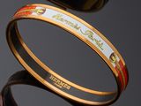three different colored bang bracelets on a black surface with reflection
