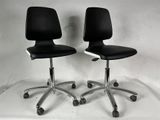 une paire de chaises de bureau noires sur roulettes, devant un fond blanc