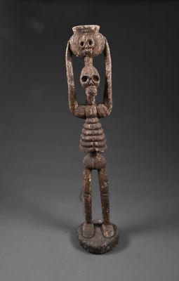 une statue en bois représentant un homme tenant un crâne sur la tête
