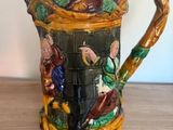 a ceramic pitcher with a bird on it sitting on a table