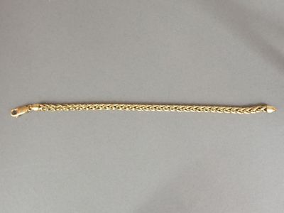 gros plan d'un bracelet en or avec une chaîne
