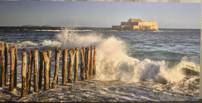 une photo d'une plage avec une clôture en bois et un château en arrière-plan
