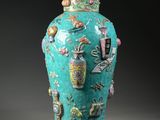 a green vase with a lid that has a picture on it