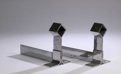 pair of metal brackets on a white surface with a gray background