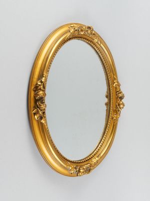 un miroir ovale avec un cadre doré accroché au mur