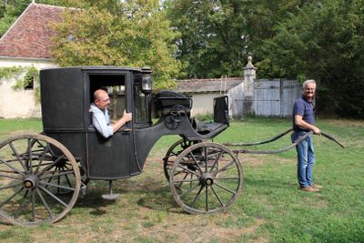 two men that are standing next to a horse drawn carriage