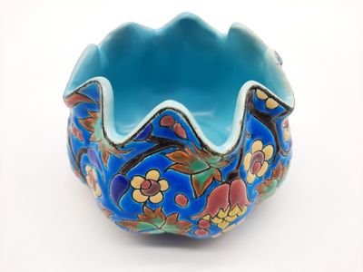 un bol bleu orné de fleurs, posé sur une surface blanche