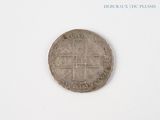 une vieille pièce de monnaie sur laquelle figure une croix, sur un fond blanc