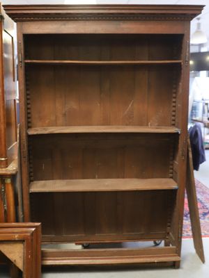 une bibliothèque en bois dont la porte est ouverte, dans une pièce