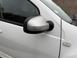 a small white car parked in a parking lot with its door open