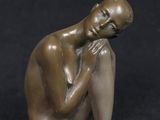 bronze sculpture of a man sitting on his knees with his hand on his chin