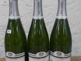 trois bouteilles de champagne posées sur une table l'une à côté de l'autre