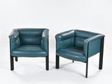 pair of blue leather armchairs with black legs on a white background