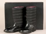 une paire de bottes en cuir noir avec une doublure rouge, posée devant une boîte noire