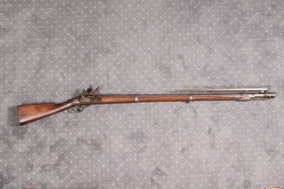 un fusil posé par terre à côté d'une arme à feu