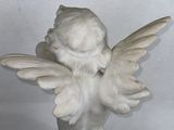 a statue of an angel holding a bird on a table