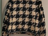 black and tan checkered jacket hanging on a hanger in a room
