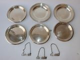 six assiettes argentées et un cintre en fil de fer posés sur une surface blanche