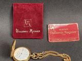 une montre de poche en or et un portefeuille rouge posés sur une table