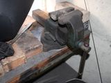 a metal clamp that is sitting on top of a piece of wood