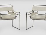 deux fauteuils en cuir blanc placés l'un à côté de l'autre sur une surface blanche