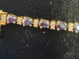 gold tone bracelet with purple glass beads and a cross charm