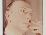 une photo en noir et blanc d'un homme en costume en train de fumer une cigarette