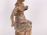 bronze statue of a woman sitting on a chair holding a flower