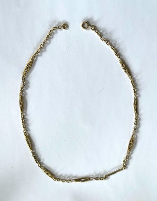 gros plan d'un bracelet en chaîne en or sur fond blanc