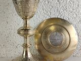 a silver chalicet and a silver plate on a table
