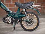 a green motorcycle that is parked in front of a brick wall