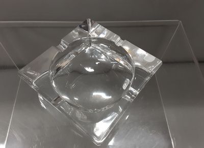 un cendrier en verre contenant une cigarette, posé sur une table