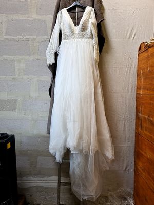 a wedding dress hanging on a clothes rack in a room