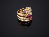 a gold ring with three different colored stones on a black surface