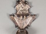 une horloge en argent accrochée au mur, sur laquelle est gravée une croix
