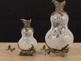 pair of silver and glass vases sitting on top of a wooden table