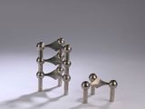 three pieces of metal on a white surface with a gray background