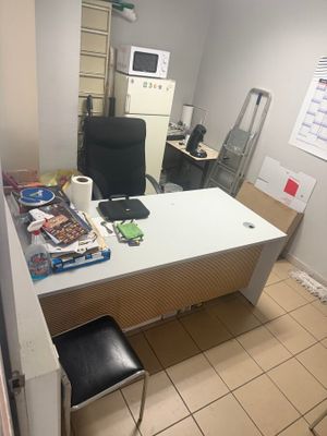 a desk with a chair and a microwave in the room