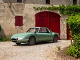 a green car parked in front of a stone building