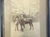 une vieille photo d'un homme debout à côté d'un cheval dans un champ