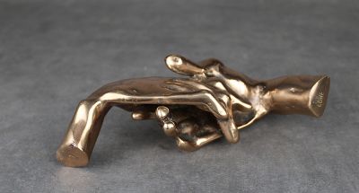 figurine en laiton représentant une main tenant un pistolet posée sur une table