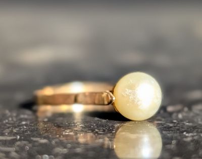une bague ornée d'une perle posée sur une table