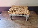 a small stool with a woven seat on top of a wooden table