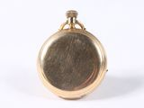 a small gold pocket watch on a white surface