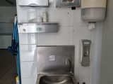 a stainless steel sink in the corner of a bathroom
