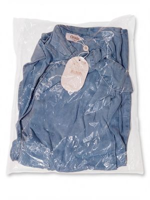 a close up of a blue shirt in a plastic bag on a white background
