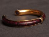 a close up of a red and gold bracelet on a black surface