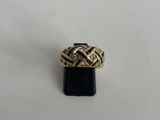 une bague en or sertie de diamants, posée sur un socle noir