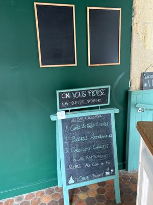 un tableau noir sur lequel est inscrit un menu, devant un mur vert