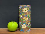 a green apple sitting next to a brown and blue vase